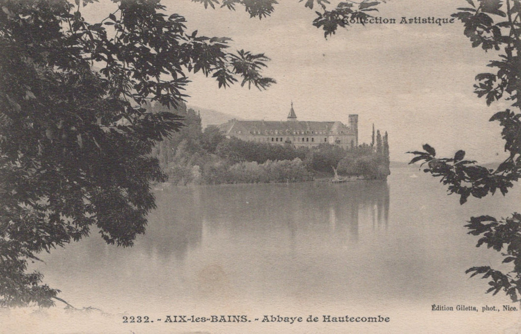 Vintage photograph of a castle or abbey across a body of water with trees framing the view.