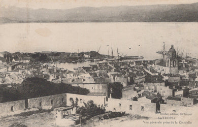 Vintage black and white photo of a coastal town with buildings and a harbor.