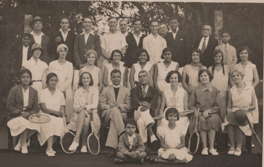 Black and white group photo of people with tennis rackets on a tennis court