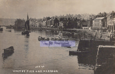 Vintage photograph of Whitby Pier and Harbour with boats and buildings.
