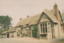 Load image into Gallery viewer, Traditional stone building with a thatched roof in a rural setting
