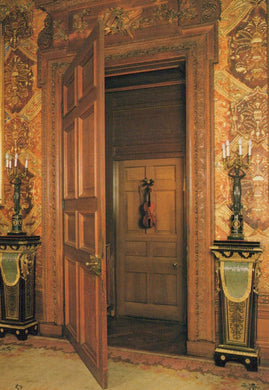 Decorative interior with open wooden door, ornate walls, and candle holders.