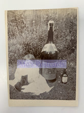 Load image into Gallery viewer, Vintage-style photo of a person sitting outdoors with a large bottle and smaller bottle, overlaid with &#39;Mo&#39;s Postcards&#39; text.
