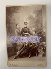 Load image into Gallery viewer, Vintage black and white photograph of three people sitting together with decorative elements.
