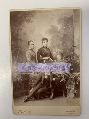 Vintage black and white photograph of three people sitting together with decorative elements.